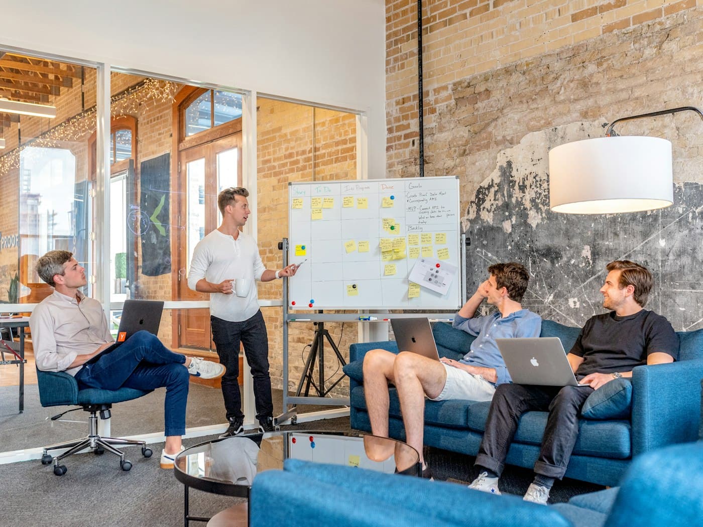 A small team in a planning workshop, one person presenting at a whiteboard of sticky notes